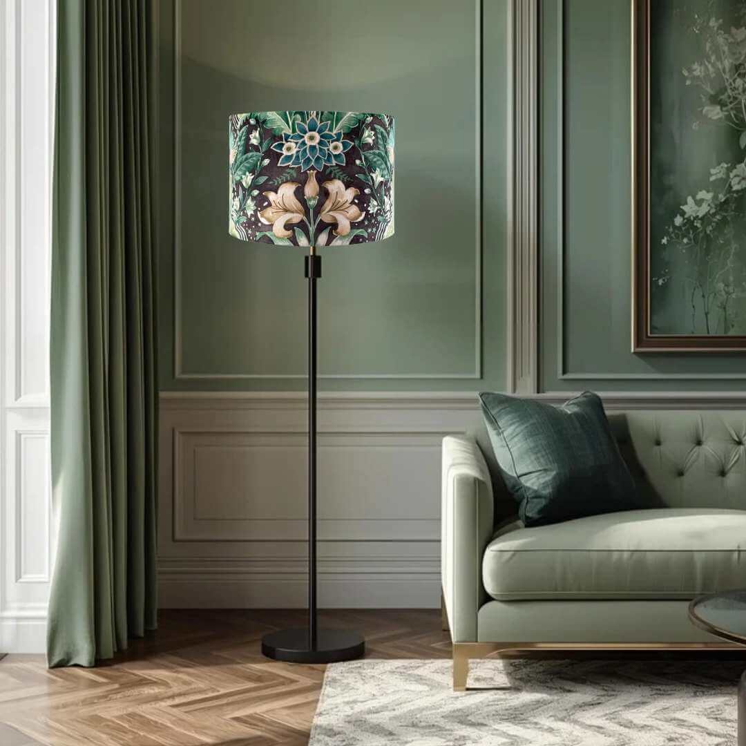 Drum lampshade with bold green floral pattern in a william morris style on a black lampbase in a living room setting