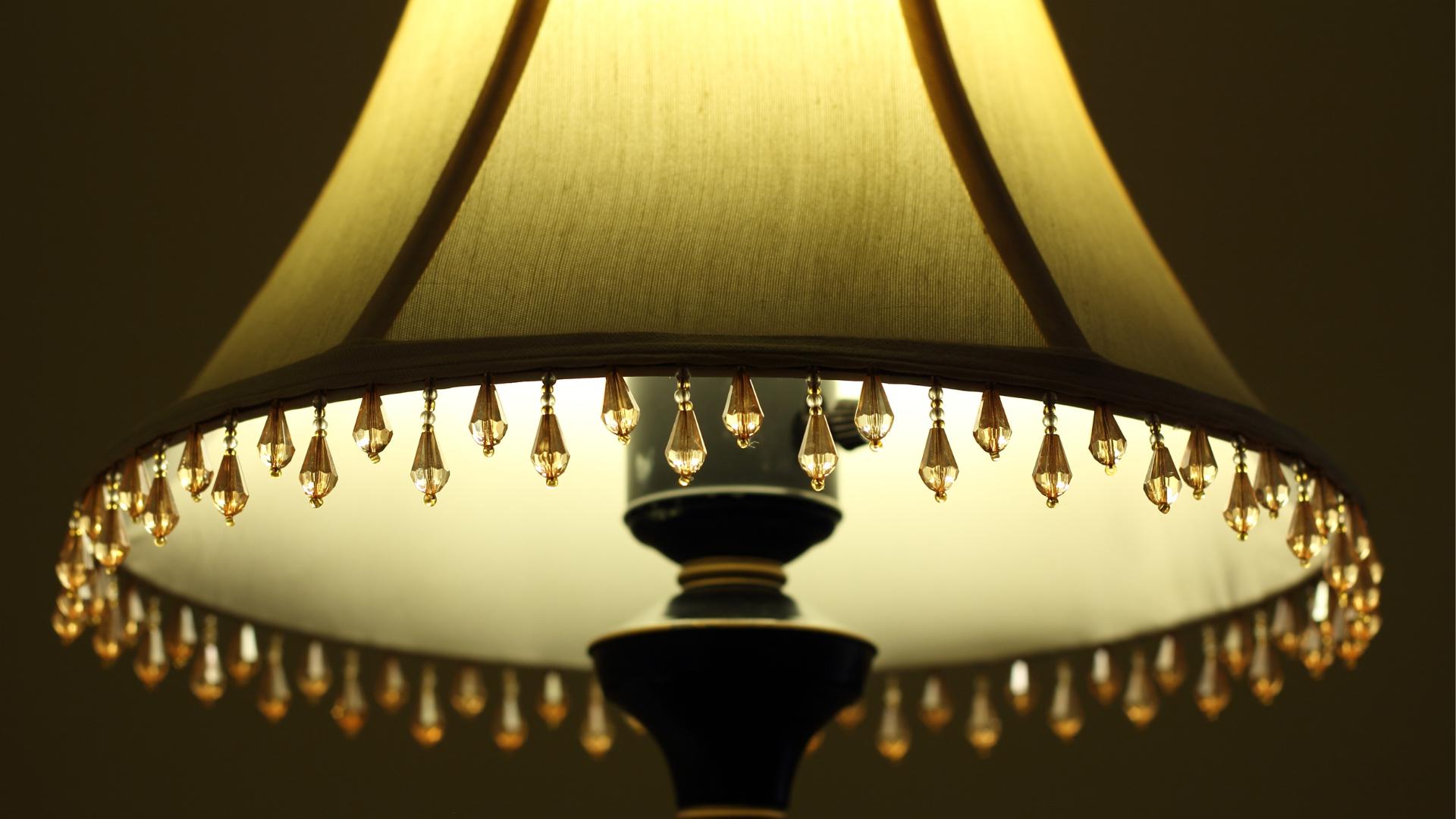 Detatailed close-up Bowed Empire green lampshade with beaded trim shown illuminated