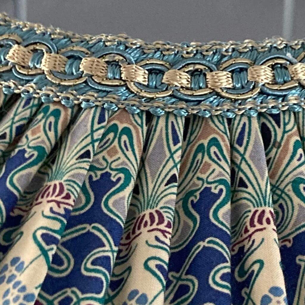 Tiffany lampshade hand pleated with Liberty Ianthe art deco fabric and deep navy fringe tassels showing detail of braid with metalic gold