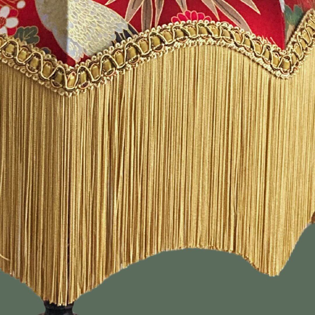 Ornate vintage style lampshade with gold fringe and red japanese fabric with cranes, florals and gold metalic accents detail of fringe