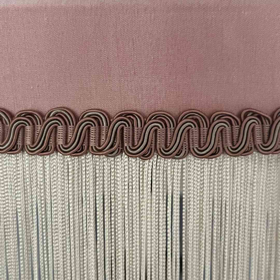 Pink silk tiffany style lampshade with ivory fringe showing detail of braid
