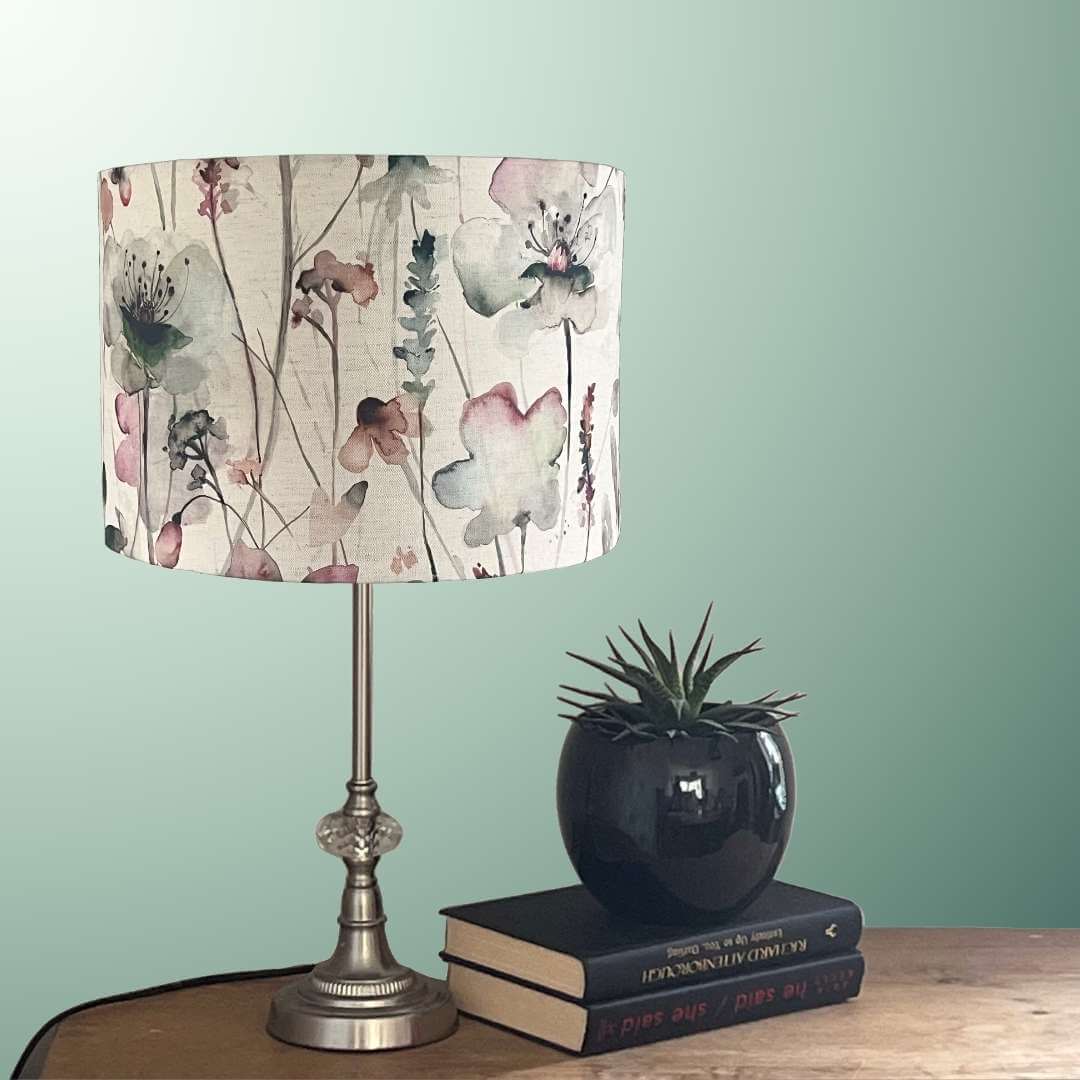 Drum lampshade in a watercolour style floral fabric by voyage maison syled on a table with plants and books