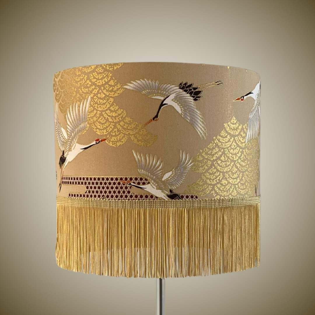 Decorative lampshade with crane design and fringe on a beige background