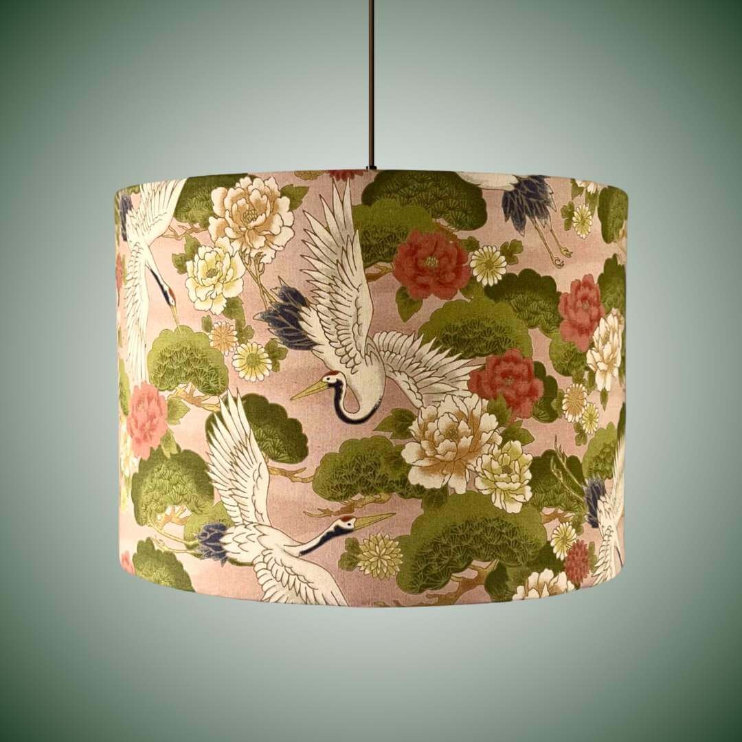 Decorative lampshade with Japanese crane and floral pattern on a peachy pink background shown on a ceiling light