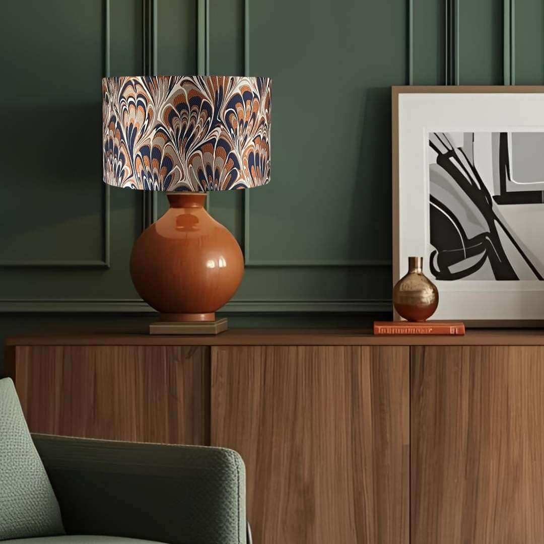Decorative lamp with marbled shade on a wooden cabinet against a green wall.