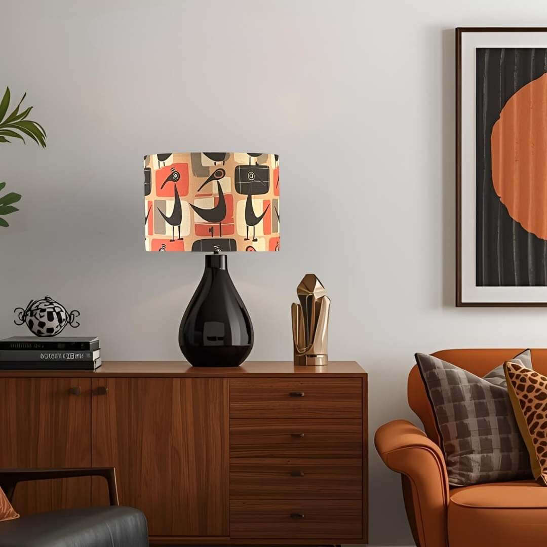 Decorative retro bird lampshade on a black base on a wooden sideboard in a living room.