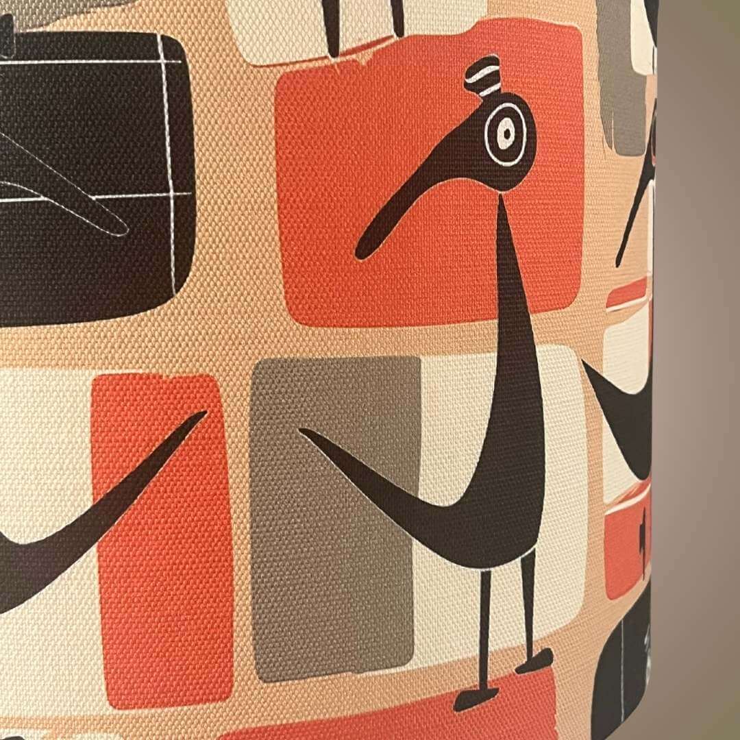 Abstract lampshade design with geometric shapes and stylised birds in orange and black, with a beige background