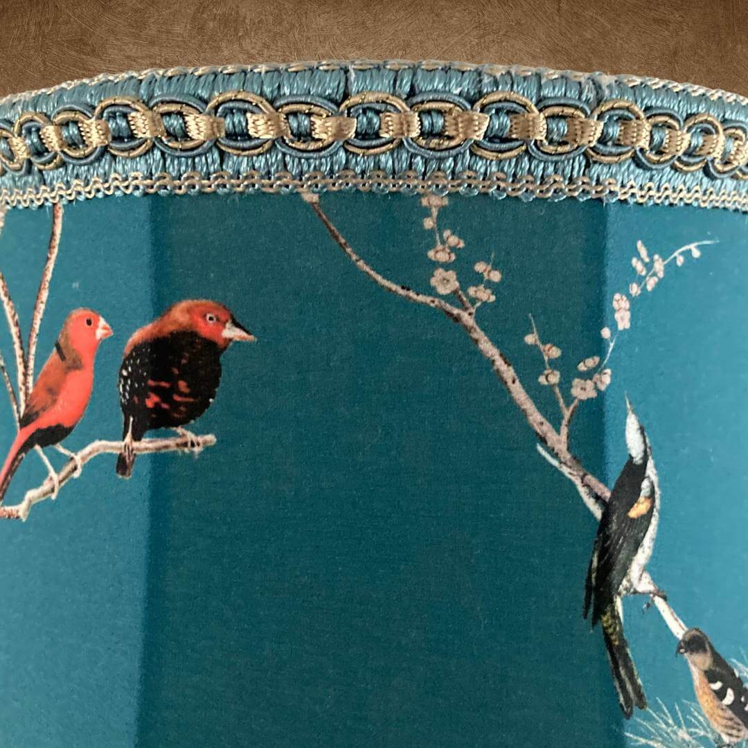 bowed empire vintage style lampshade with scalloped base, teal fabric and colourful garden birds, trimmed with a smoke grey beaded trim and braid with gold details, close up of braid and top