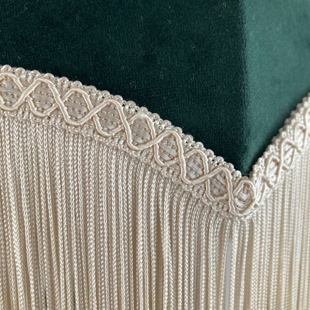 Dark green velvet vintage style dome or parachute lampshade with a deep ivory fringe showing a close up of fringe and braid