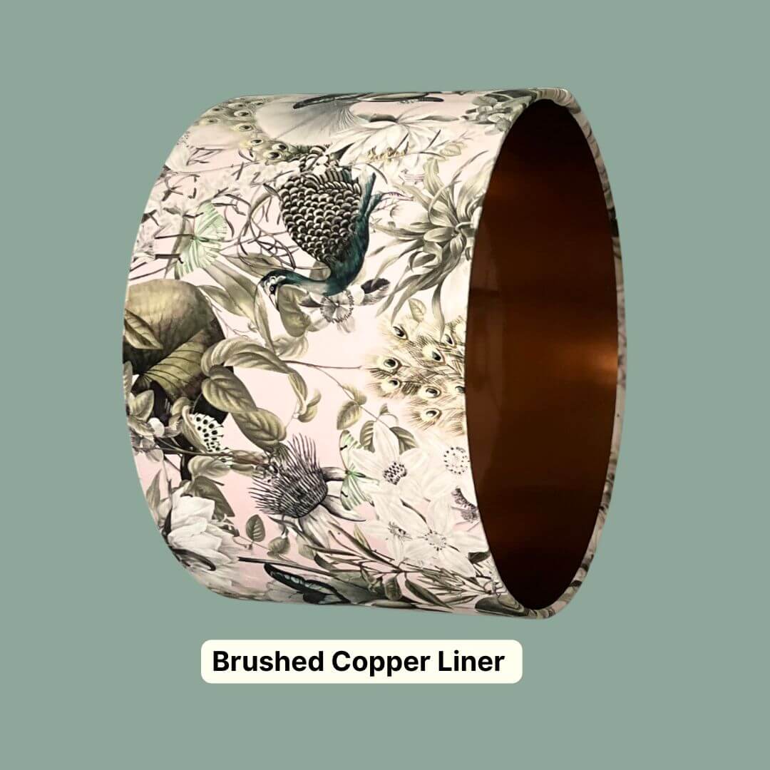 Velvet drum lampshade with a detailed botanical print with peacocks, butterflies and florals in pale pink, sage green and teal. Featuring a brushed copper liner inside. 