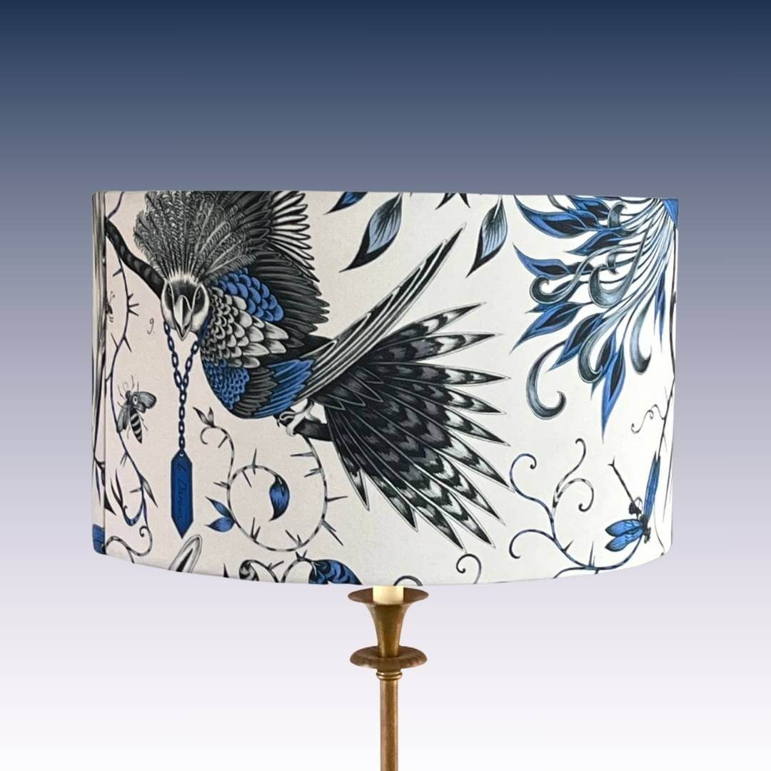 Emma J Shipley Audubon Drum Lampshade featuring exotic birds and foliage in shades of blue on a white background on standard lamp