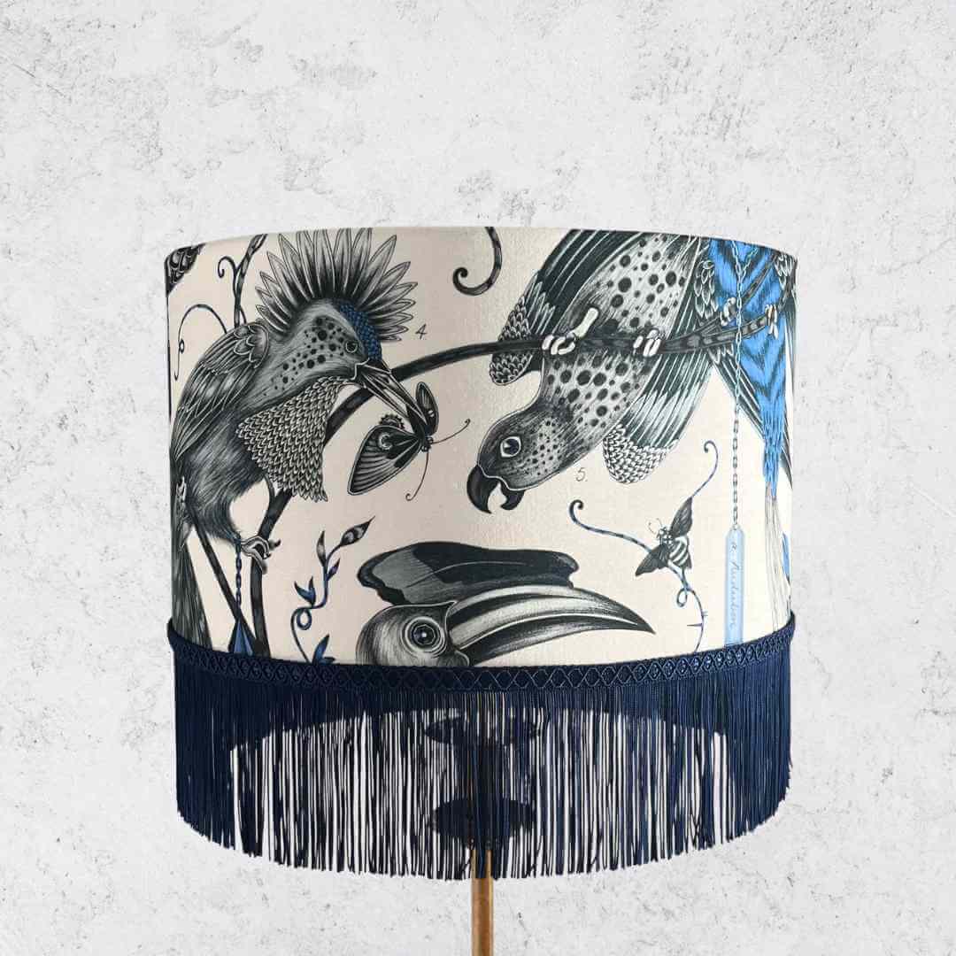 Emma J Shipley Audubon Drum Lampshade featuring exotic birds and foliage in shades of blue on a white background with Dark Blue fringe, topped with braid.