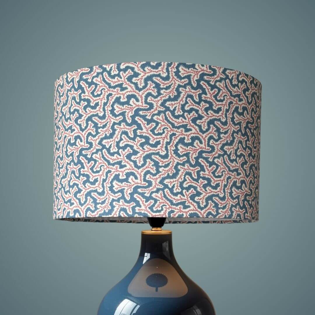 Drum lampshade made with Ian Sanderson Jubilee fabric, a small print design based on a seaweed pattern shown on a blue lampbase