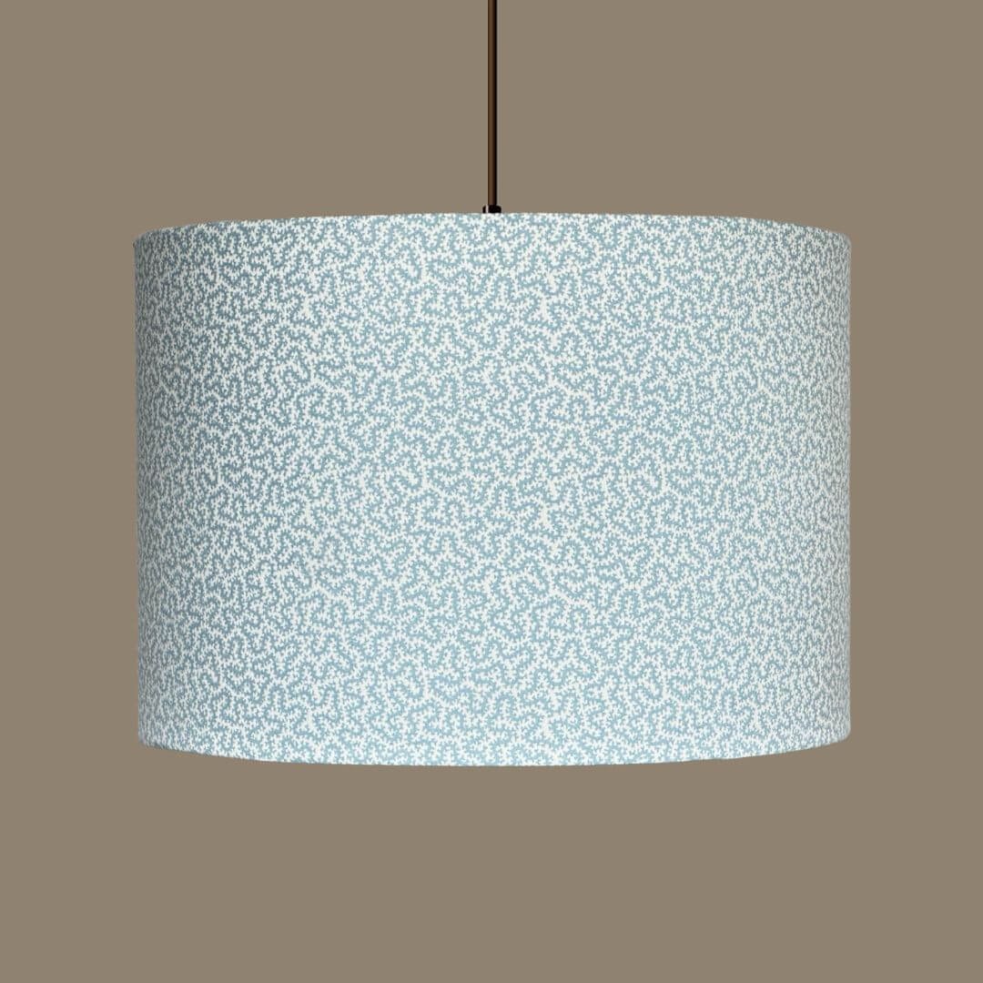Drum lampshade crafted from Ian Sanderson Petra fabric in Chalk Blue. A small-scale abstract pattern of light blue and white, shown on a ceiling pendant.