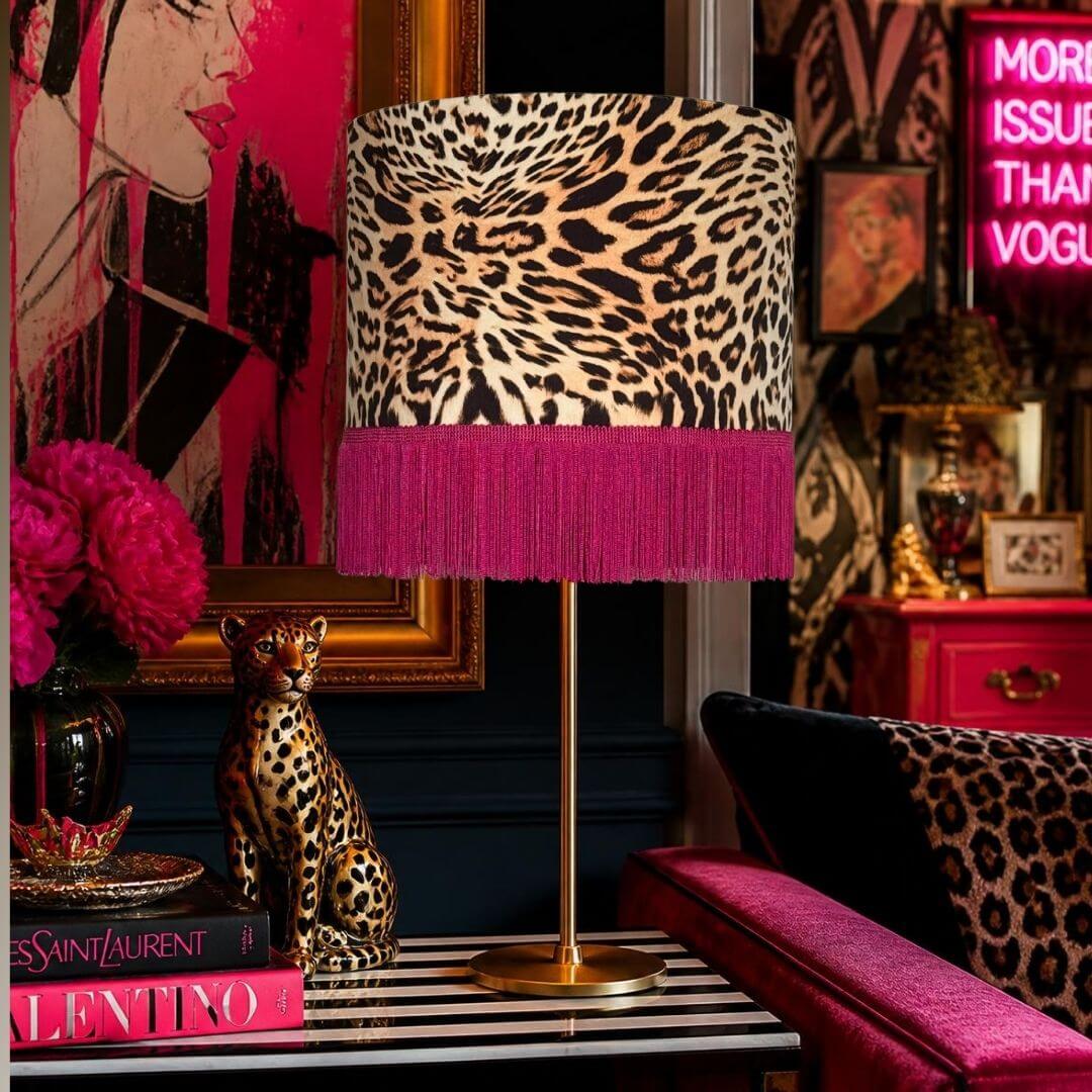 Drum lamp shade featuring a leopard print velvet with a hot pink fringe displayed on a gold stem base in a maximalist scheme.