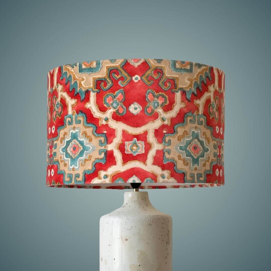 Linwood omega velvet kami drum lampshade in chilli shown on a marble lamp base