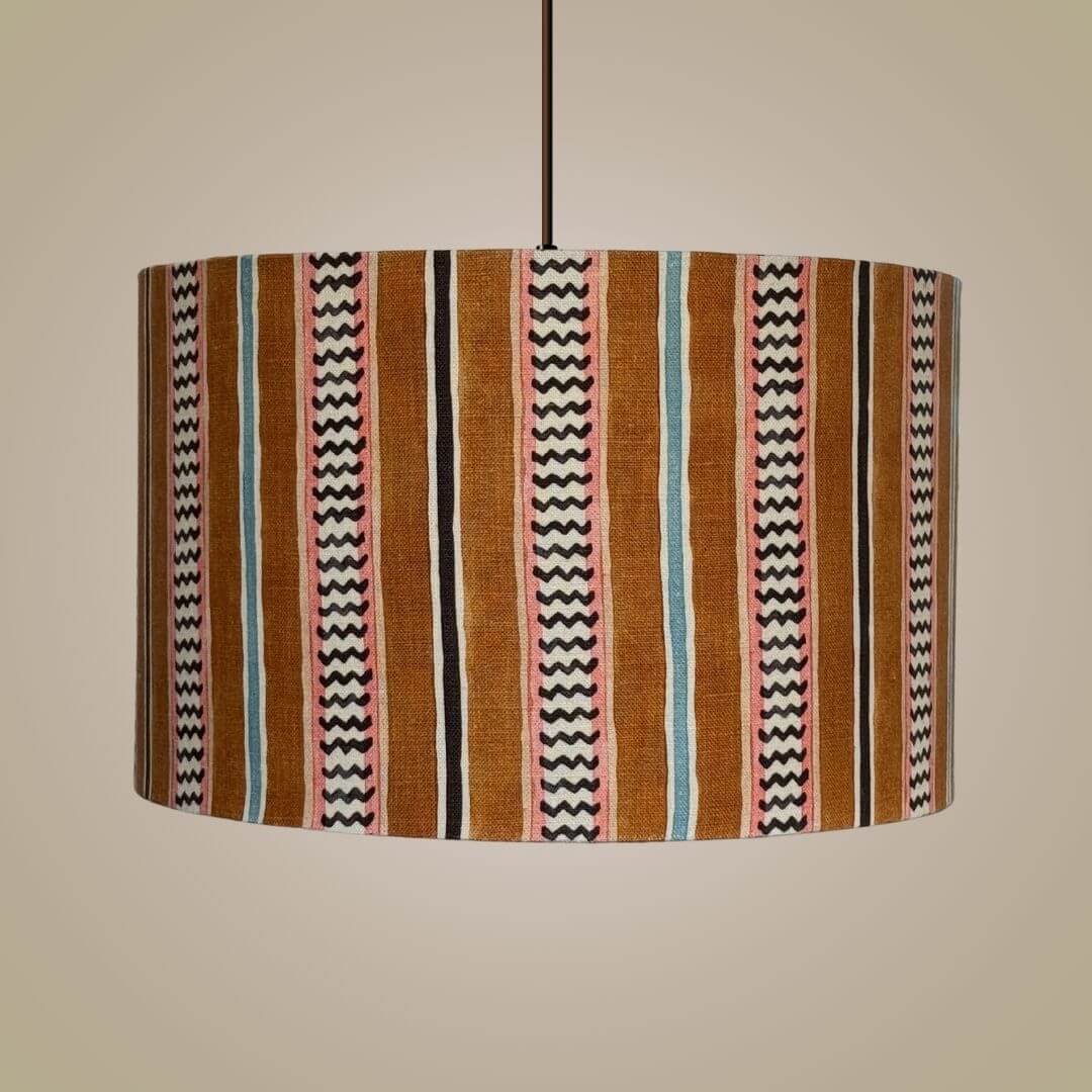 drum lampshade in Linwood hire wire fabric. Featuring an alternating chevron and solid stripe pattern, shown hung as a ceiling light