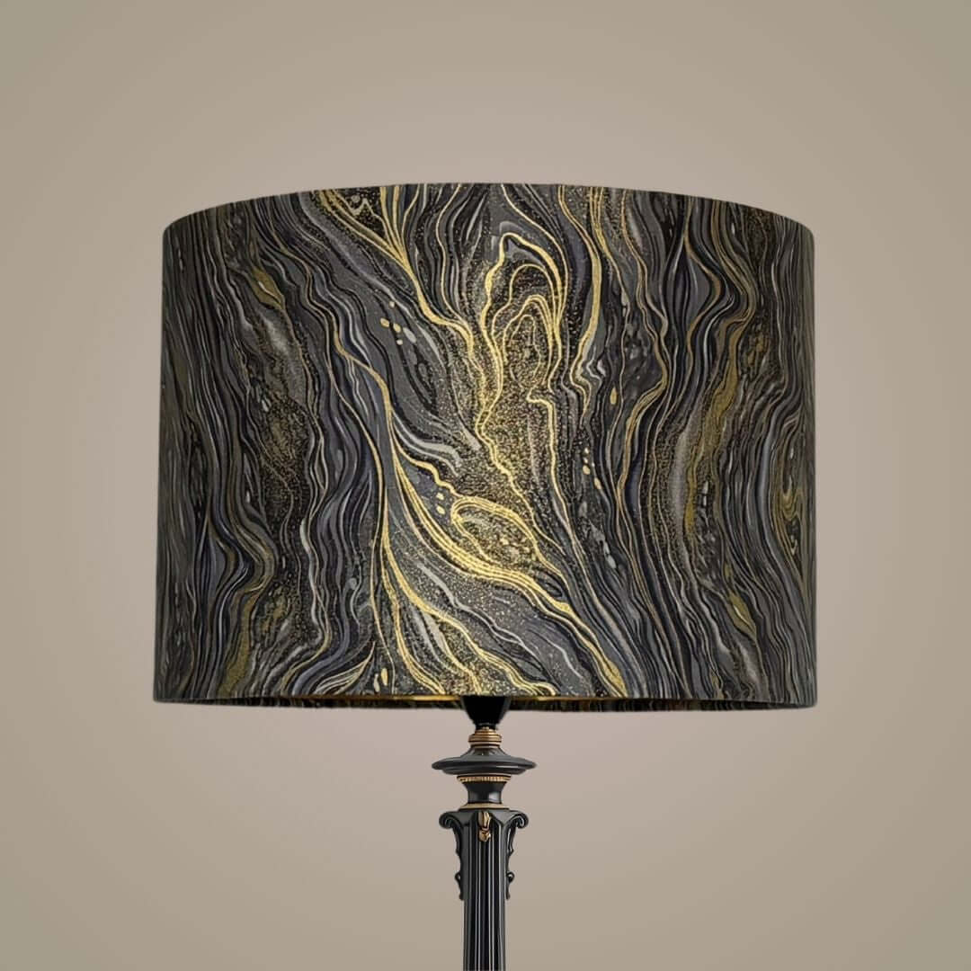 A floor lamp with a large cylindrical drum lampshade featuring a black, silver, grey, and gold marbled pattern