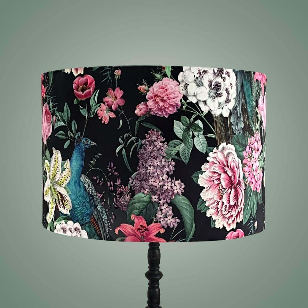 Velvet drum lampshade on a lampstand in a Romantic design with peacocks and lush floral blossoms on a black background