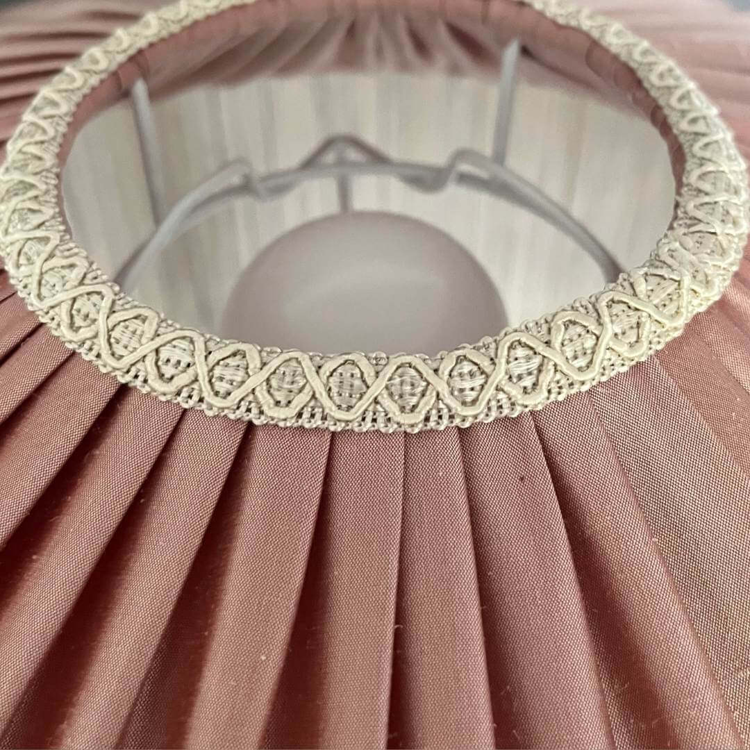 Pink silk tiffany style lampshade with ivory fringe showing detail of braid