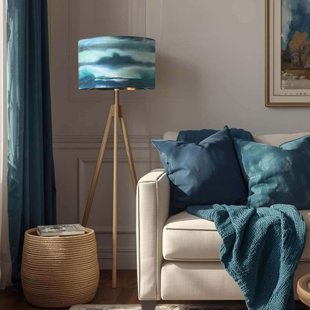 Living room with a beige sofa, blue cushions, and a lamp with a fjord watercolor shade.