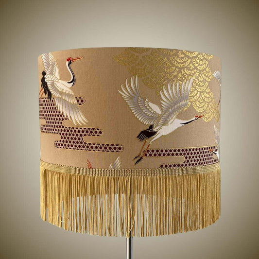 Decorative lampshade with crane design and fringe on a beige background
