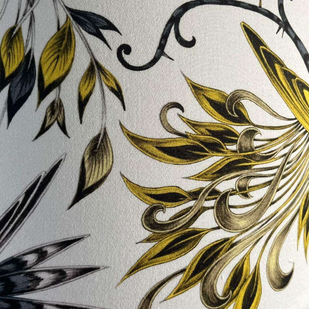 Emma J Shipley Audubon Drum Lampshade featuring exotic birds and foliage in shades of gold, yellow, beige, and charcoal grey on a white background, showing detail of foliage