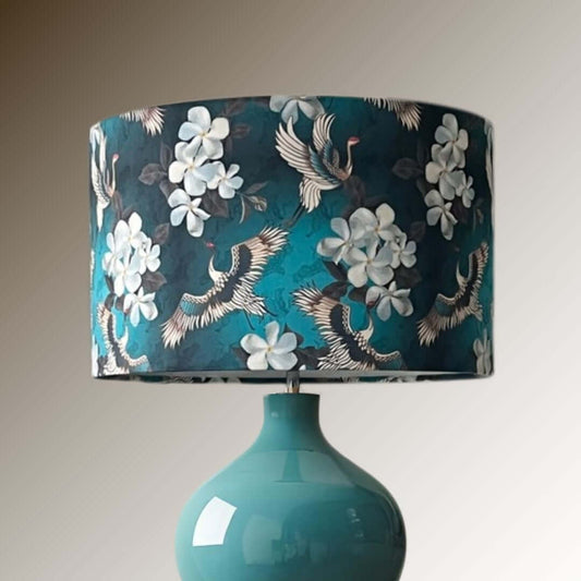 Turquoise and blue Japanese crane and floral design drum lampshade on a blue base