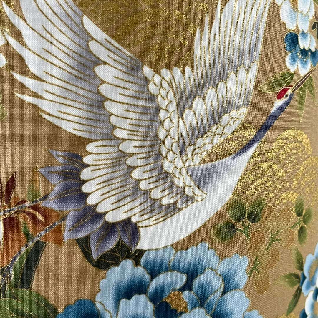 Japanese cranes fabric with blue, bronze & white florals on a soft gold background