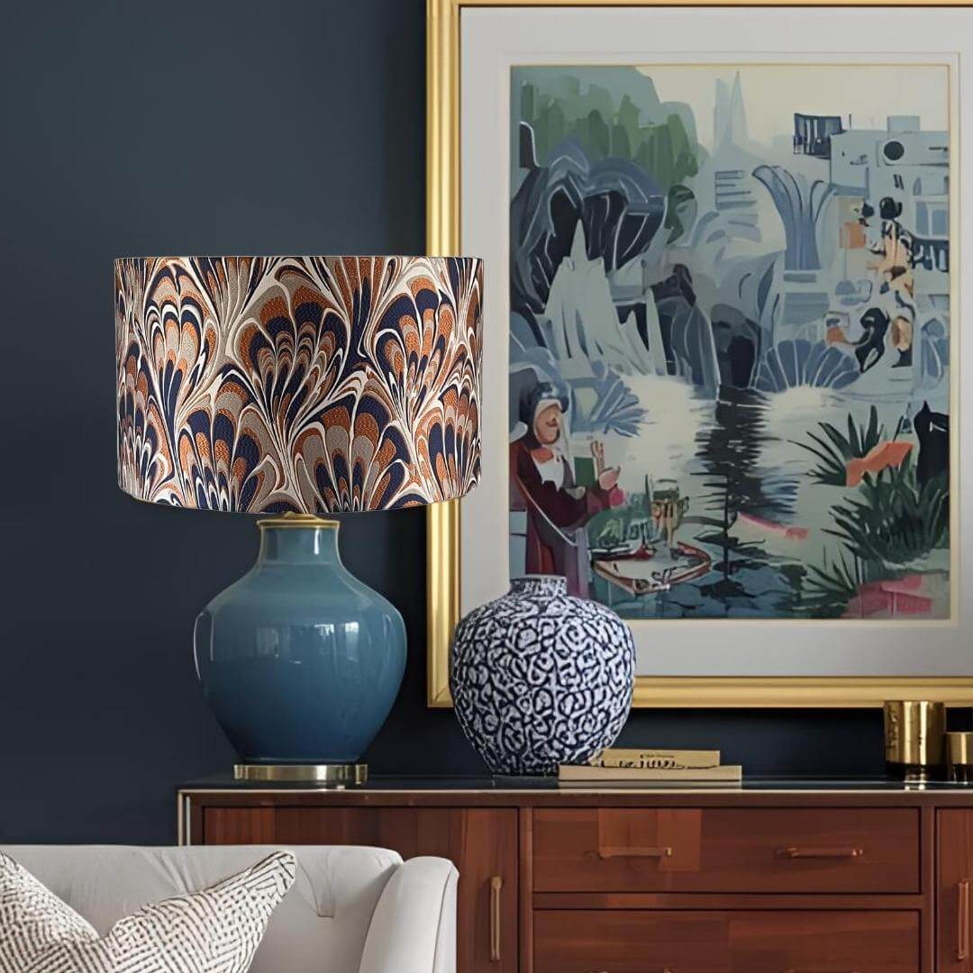 Decorative lamp with marbled shade and blue base next to a framed artwork on a dark wall.