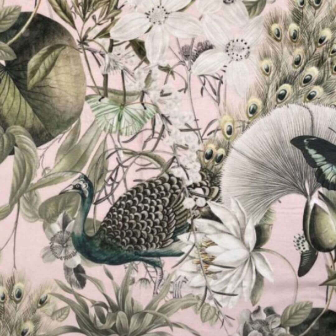 A close-up of a velvet fabric featuring a peacock, butterflies, lotus flowers, and on a soft pink background.